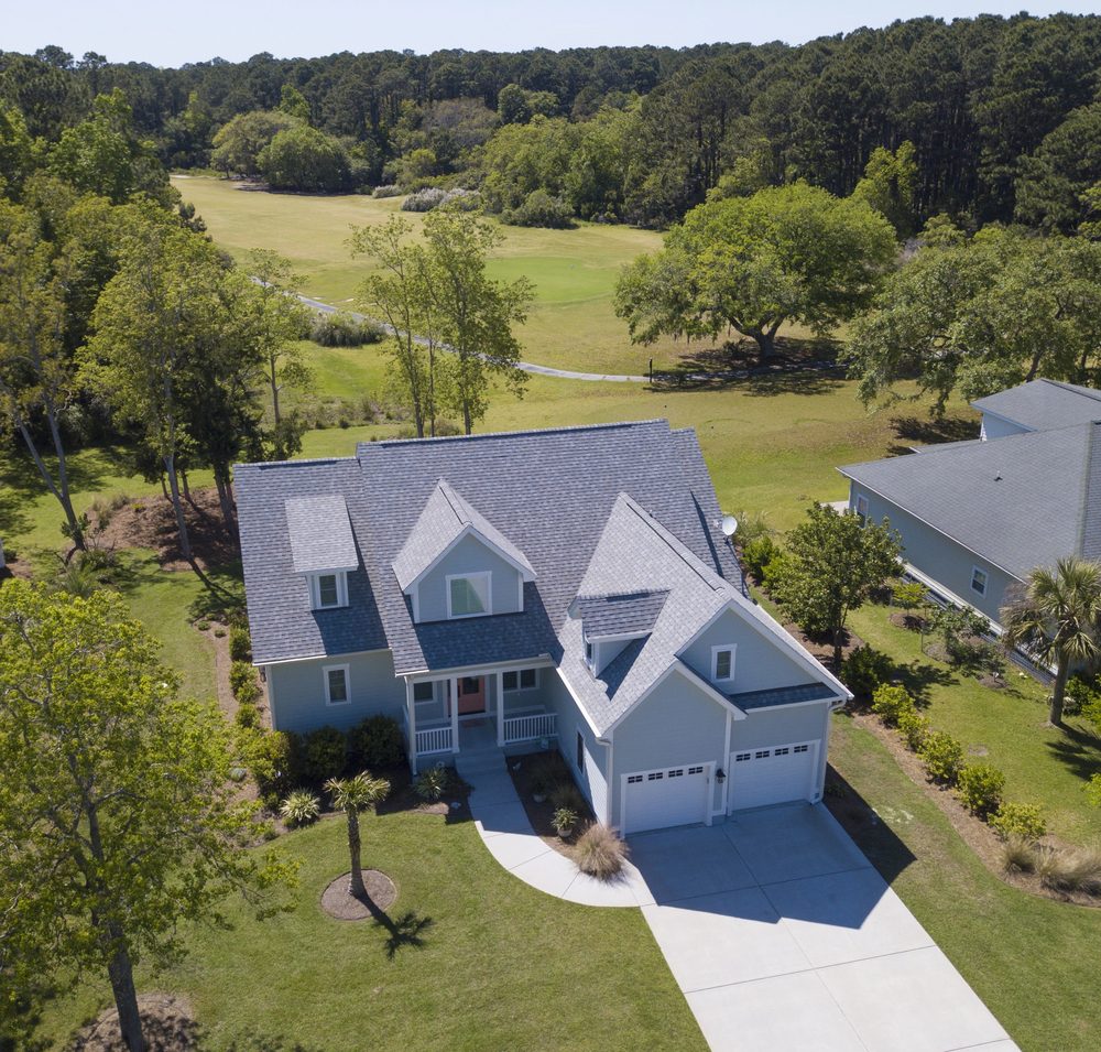 Aerial view of blue home with gray shingle roof