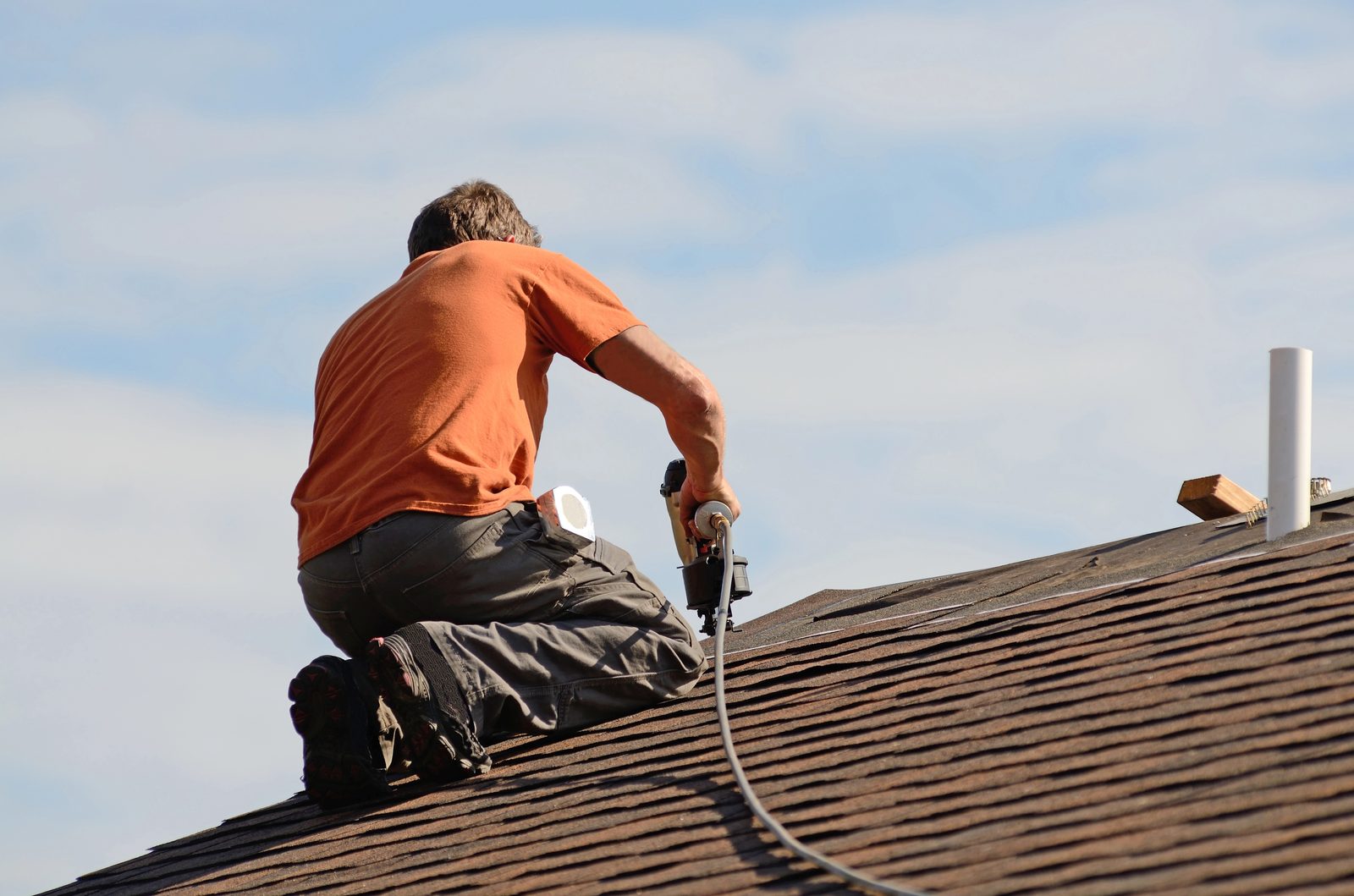 Roofer installing shingles with nail gun