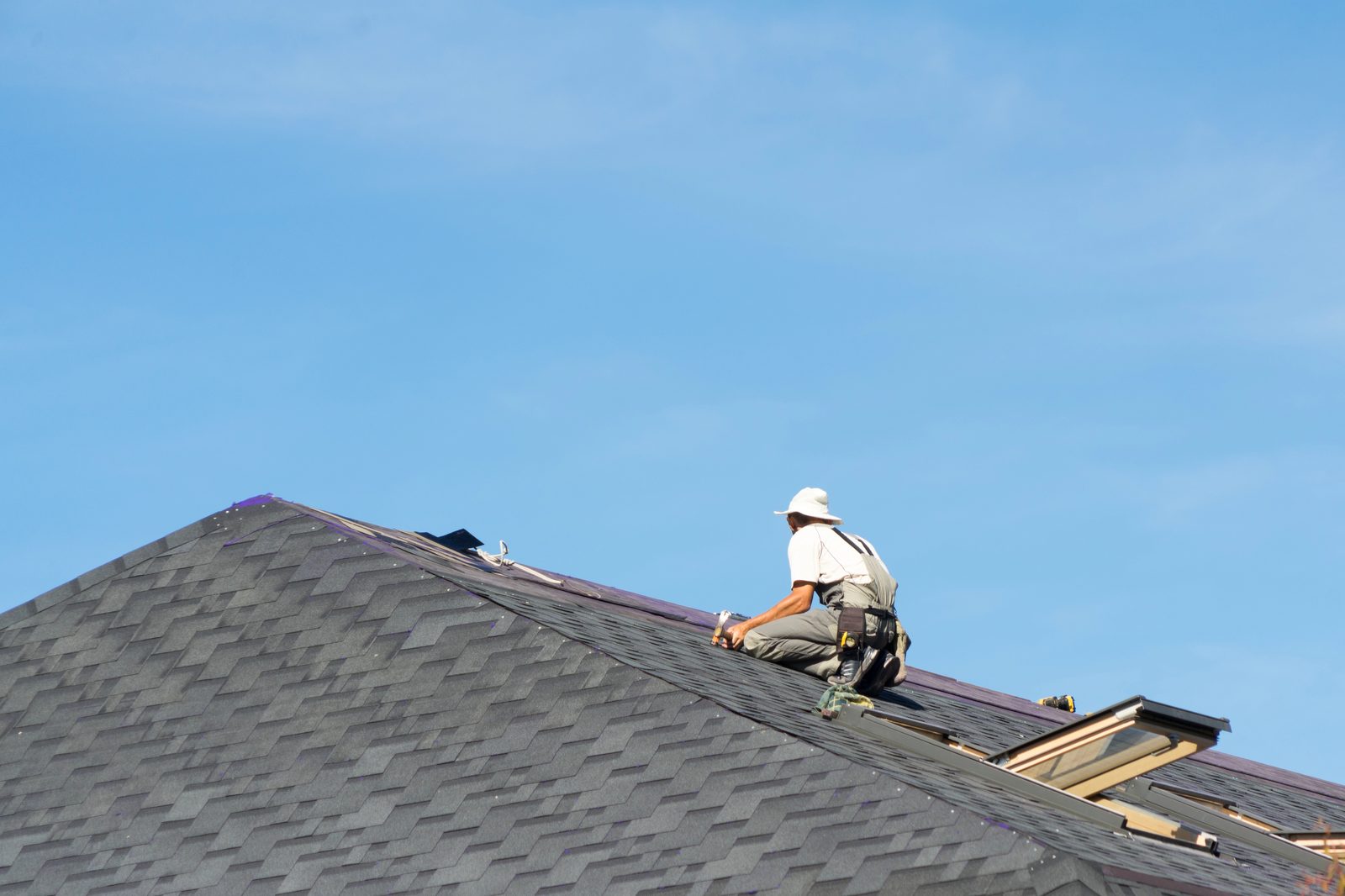Professional roofer installing asphalt shingles