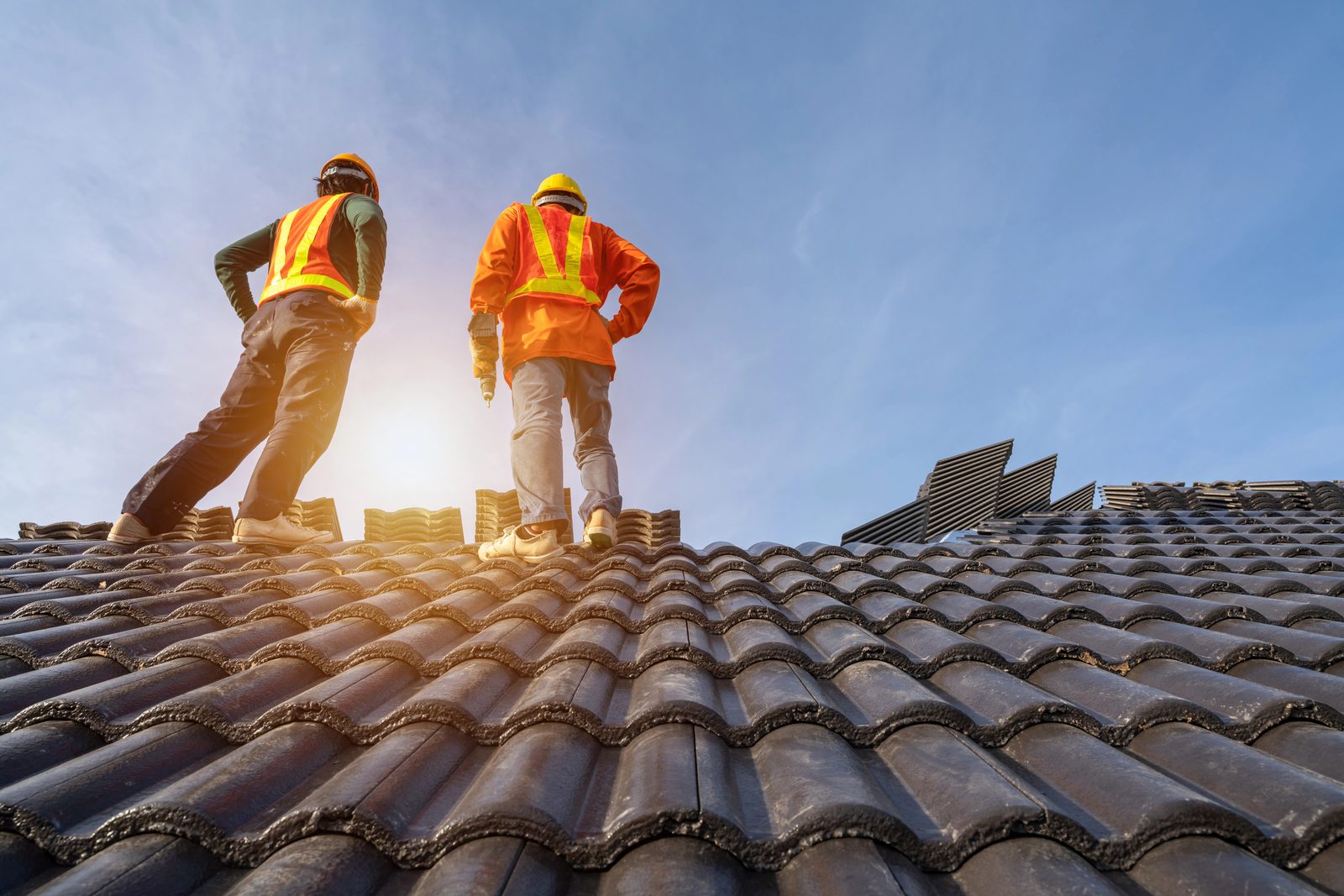 Roofing crew inspecting tile roof with safety gear