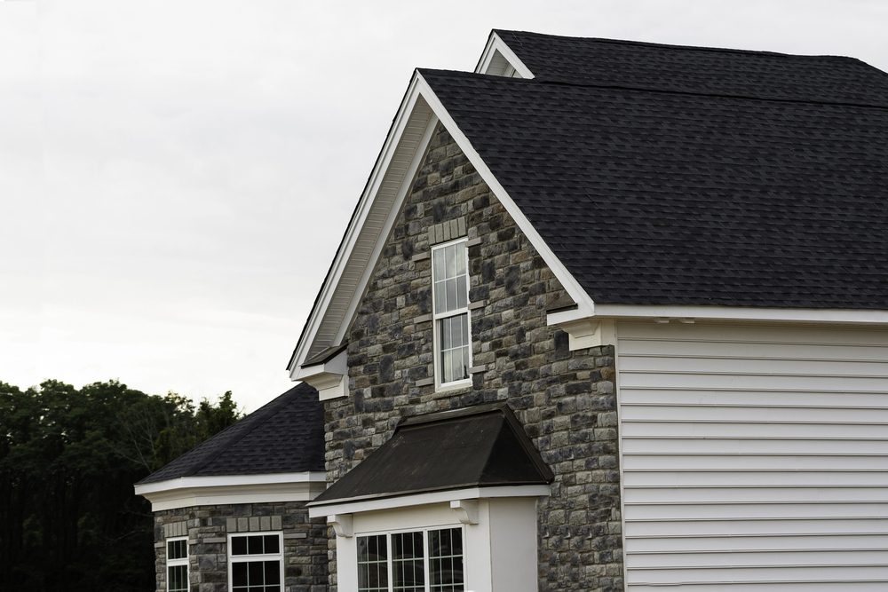 Stone facade home with dark asphalt shingles