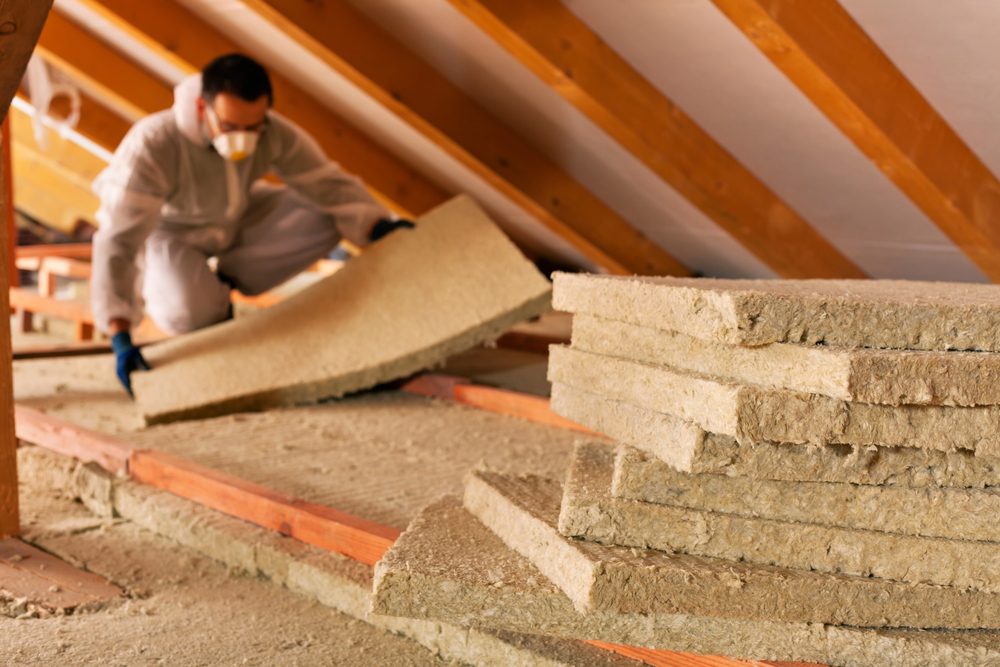 Worker installing mineral wool insulation in attic